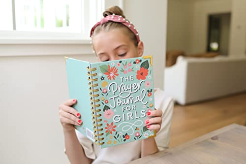Teen girl reading The Prayer Journal for Teen Girls with floral cover, seated at a table in a cozy, well-lit room