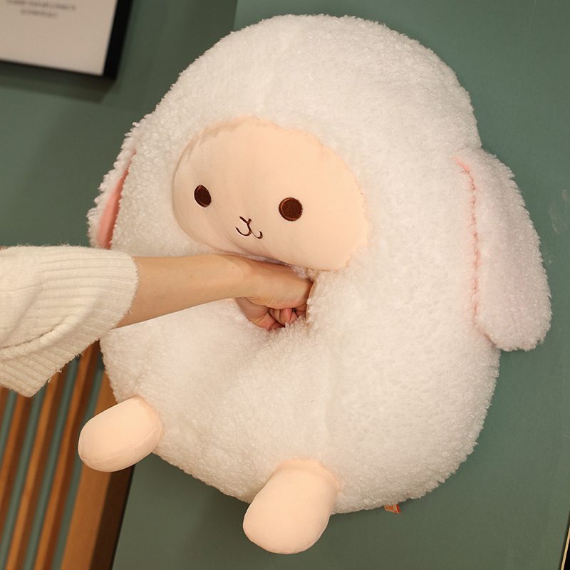 Round sheep plushie with peach face and hand inserted into its belly, suggesting a warmer feature.
