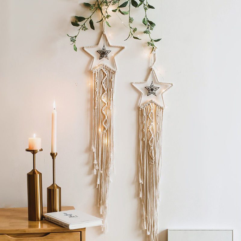 Two star-shaped dream catcher wall decorations with macramé tassels, string lights, and candle-lit decor.