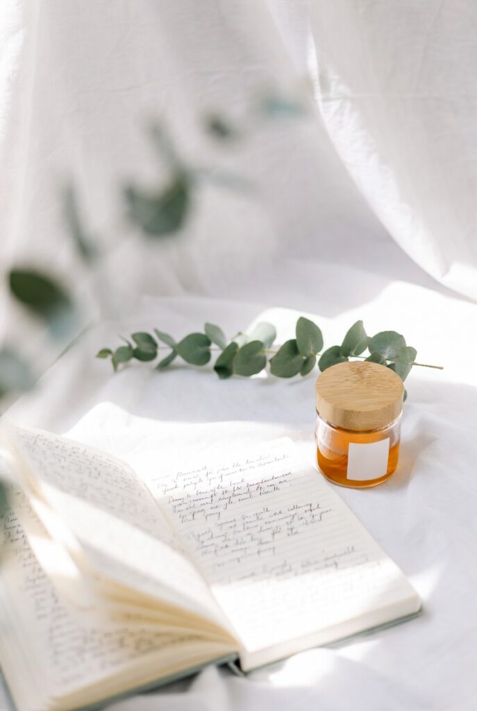 Eczema Flare-Up Diary: Month-by-Month Reflections & Healing Progress 2 Open handwritten journal with glass honey jar and fresh eucalyptus on white linen in gentle sunlight, representing TCM vs Western skincare comparison